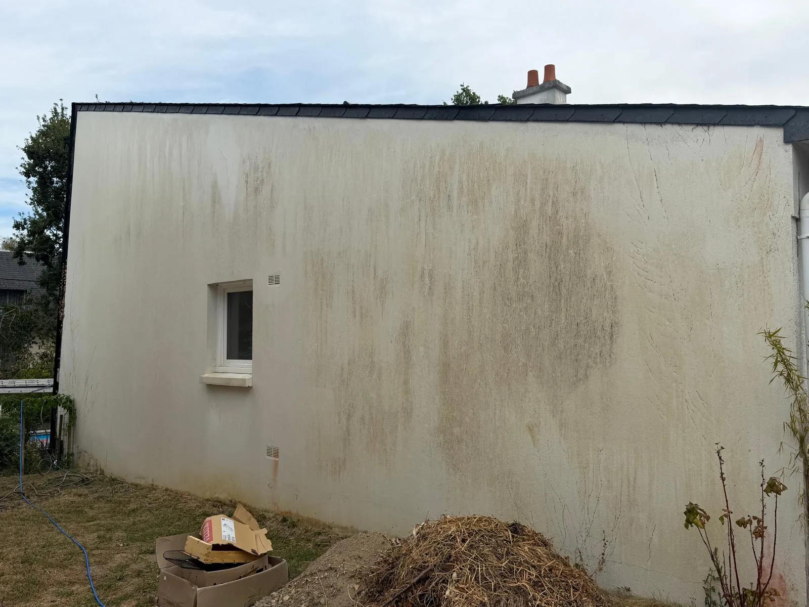 Traces et salissures sur le pignon à fenêtre blanche avant nettoyage