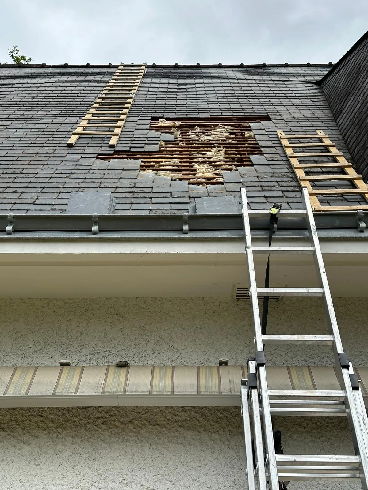 Toiture en ardoises ouverte, avec liteaux et échelles de toit visibles