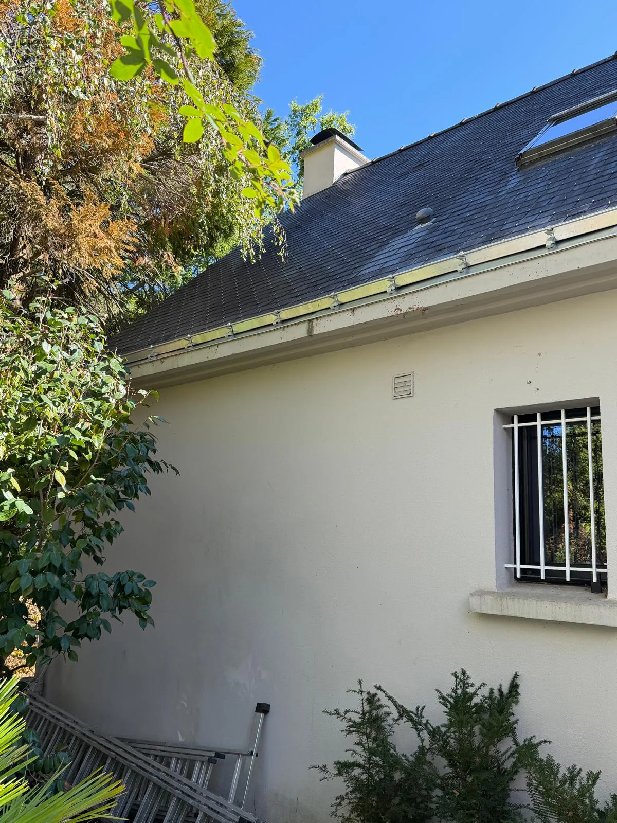Vue d’une toiture en ardoises et de sa gouttière côté jardin
